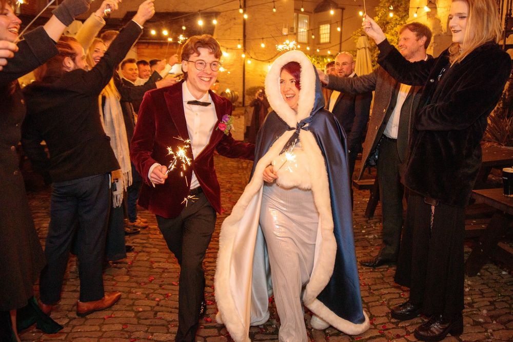 Wedding celebration with guests forming tunnel of sparklers for couple's exit.