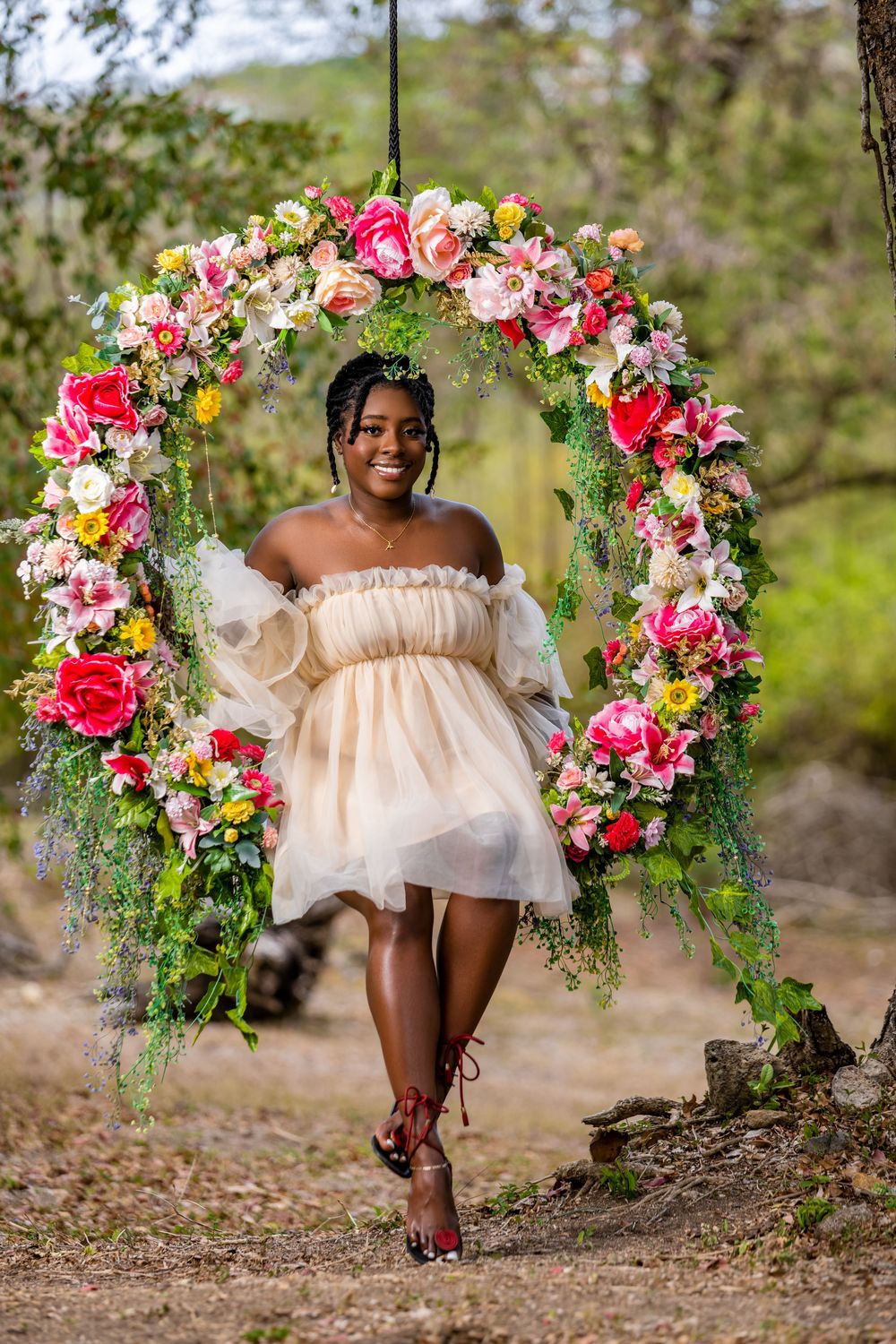 A dreamy portrait featuring an off-shoulder white dress against a floral arch with pink and coral blooms in nature.