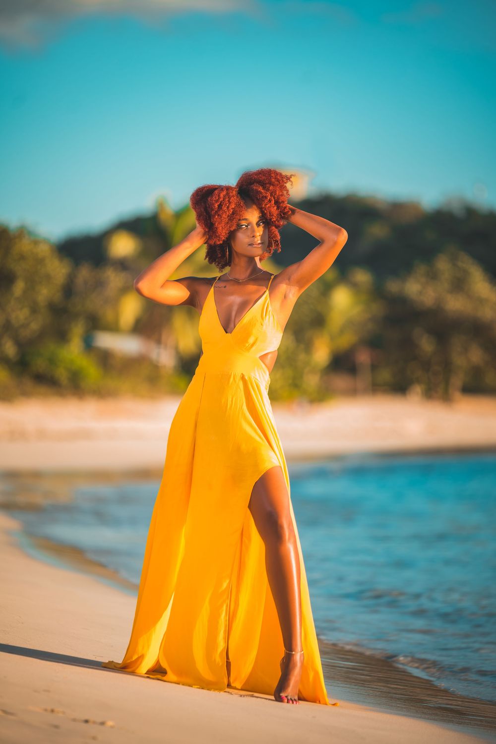 Stunning yellow flowing maxi dress photographed during golden hour on beach.