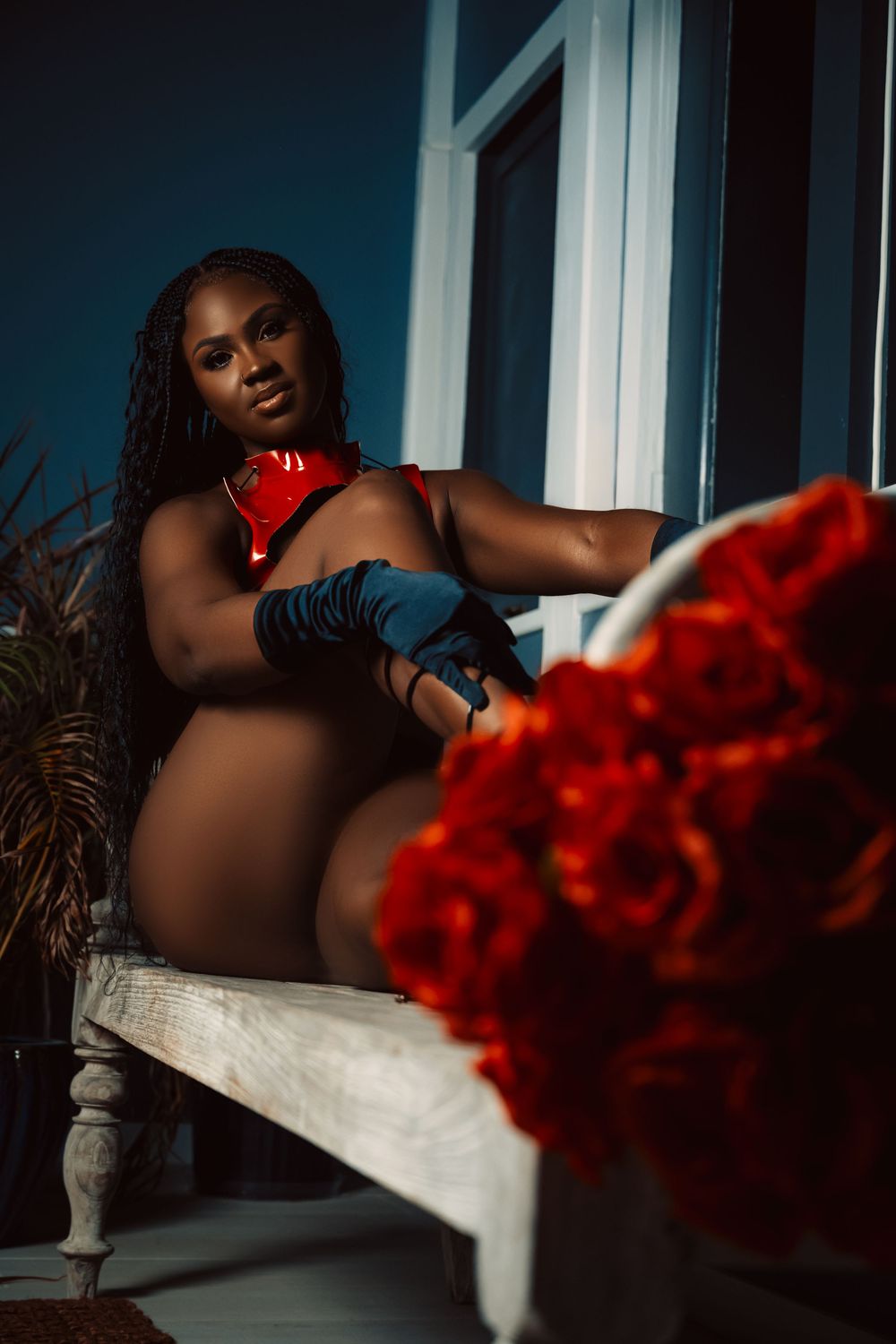 Dramatic portrait with red roses and black gloves in moody lighting.