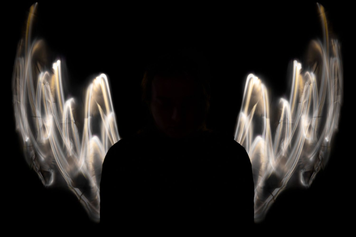 Abstract light pattern resembling angel wings against dark background.