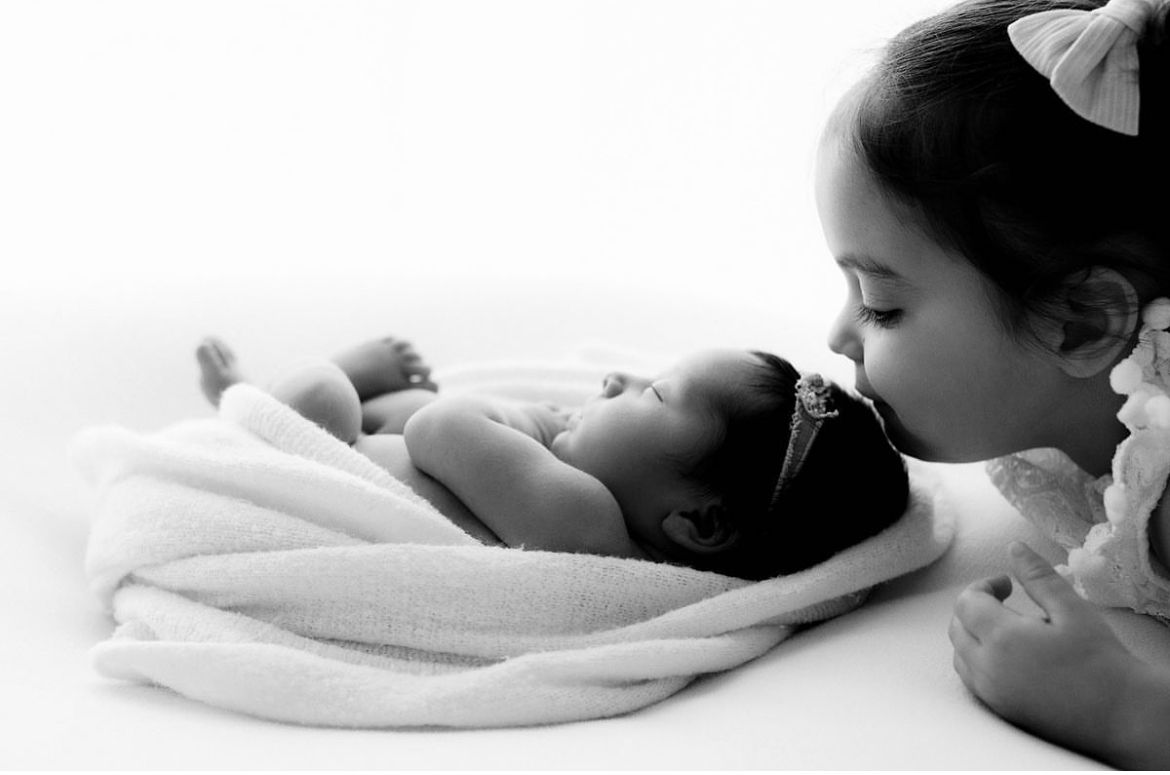 A tender black and white monochrome photograph showing a baby wrapped in soft white towels.