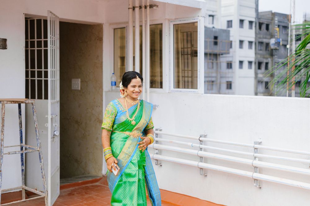 Woman in bright green silk saree standing on a balcony of modern building.