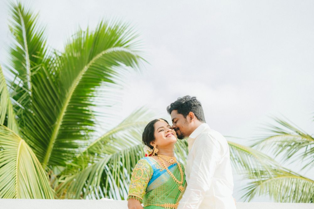A romantic moment between newlyweds against a backdrop of palm trees on a tropical beach.