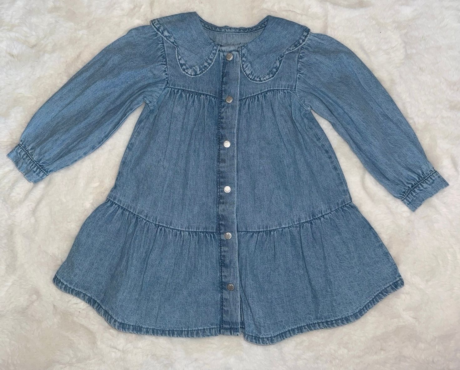 Light blue denim button-up dress with gathered waist laid flat on white surface.