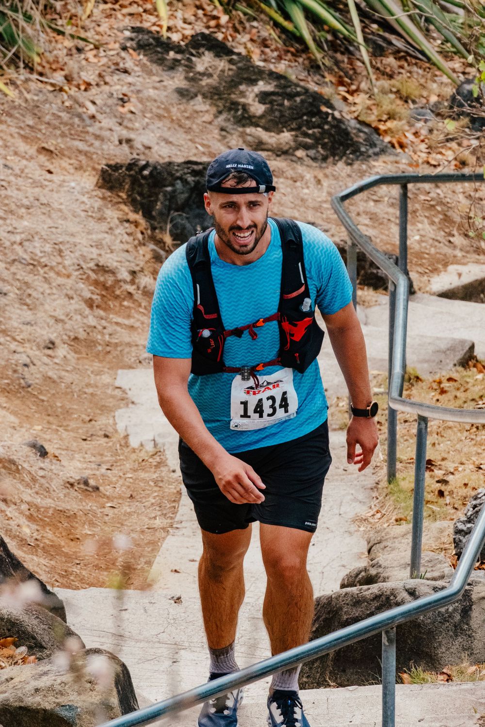 Trail runner ascending stone steps during a mountain race wearing blue shirt and race bib number 1434.