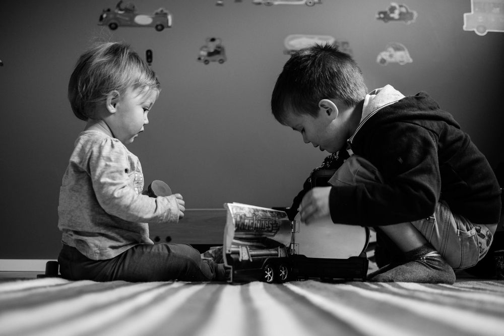Deux enfants, frère & soeur, qui jouent ensemble avec des petites voitures.