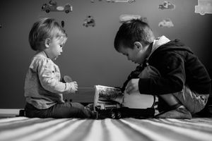 Deux enfants, frère & soeur, qui jouent ensemble avec des petites voitures.