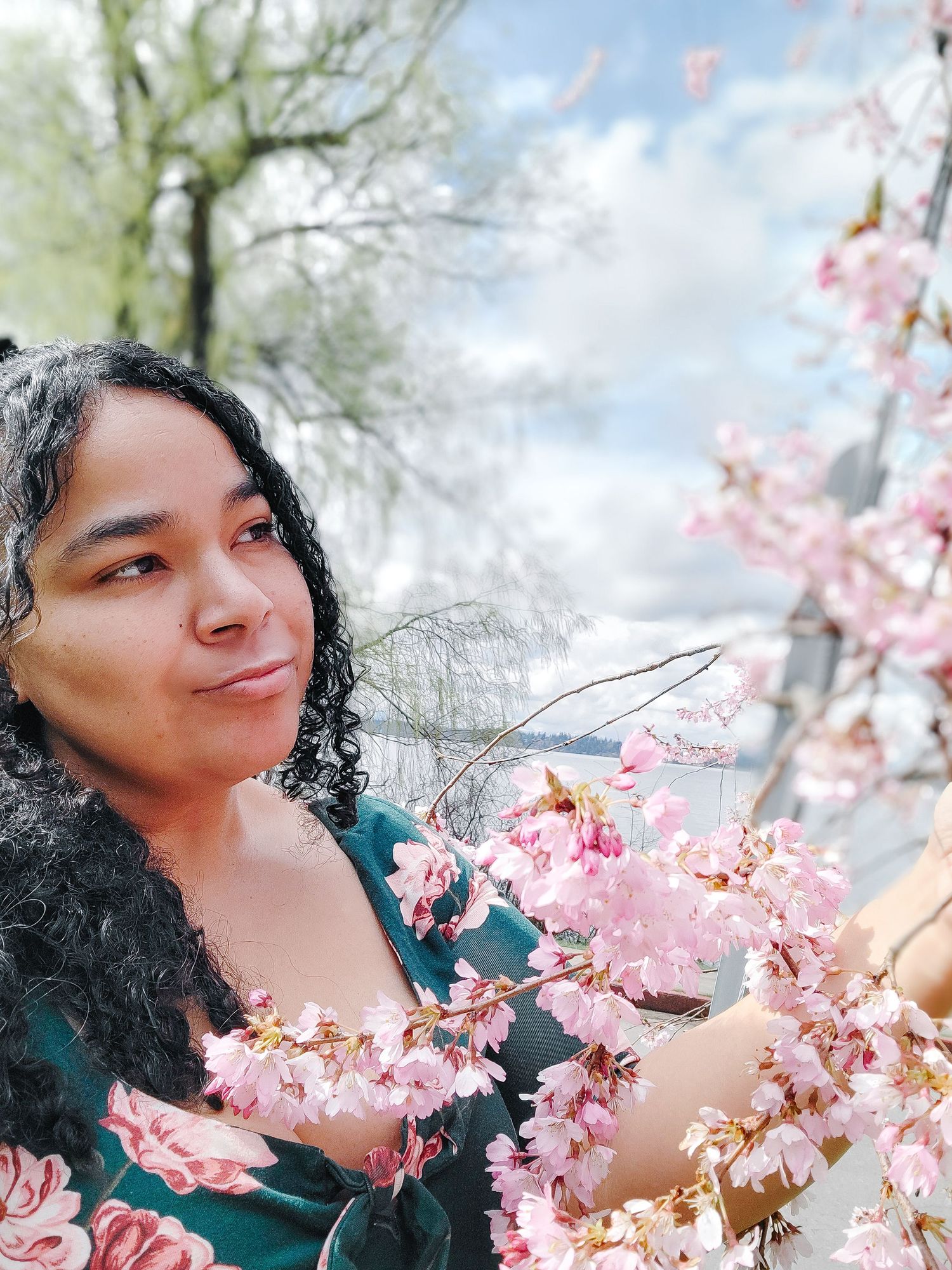 Soft and dreamy headshot of a woman surrounded by cherry blossom branches. Intimate spring portrait with pastel floral tones.