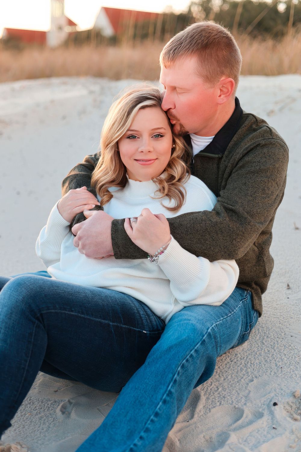 Couple sharing intimate moment while sitting on sandy beach at sunset. Engagement session. Couples photography.