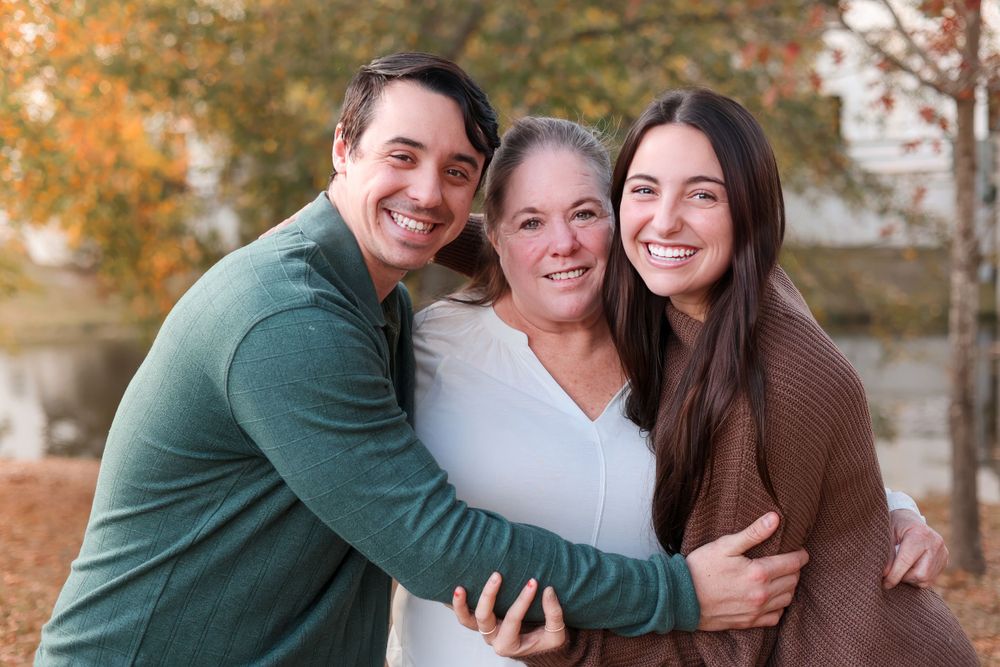 Three people sharing warm embrace during fall family photoshoot. Family photography session.