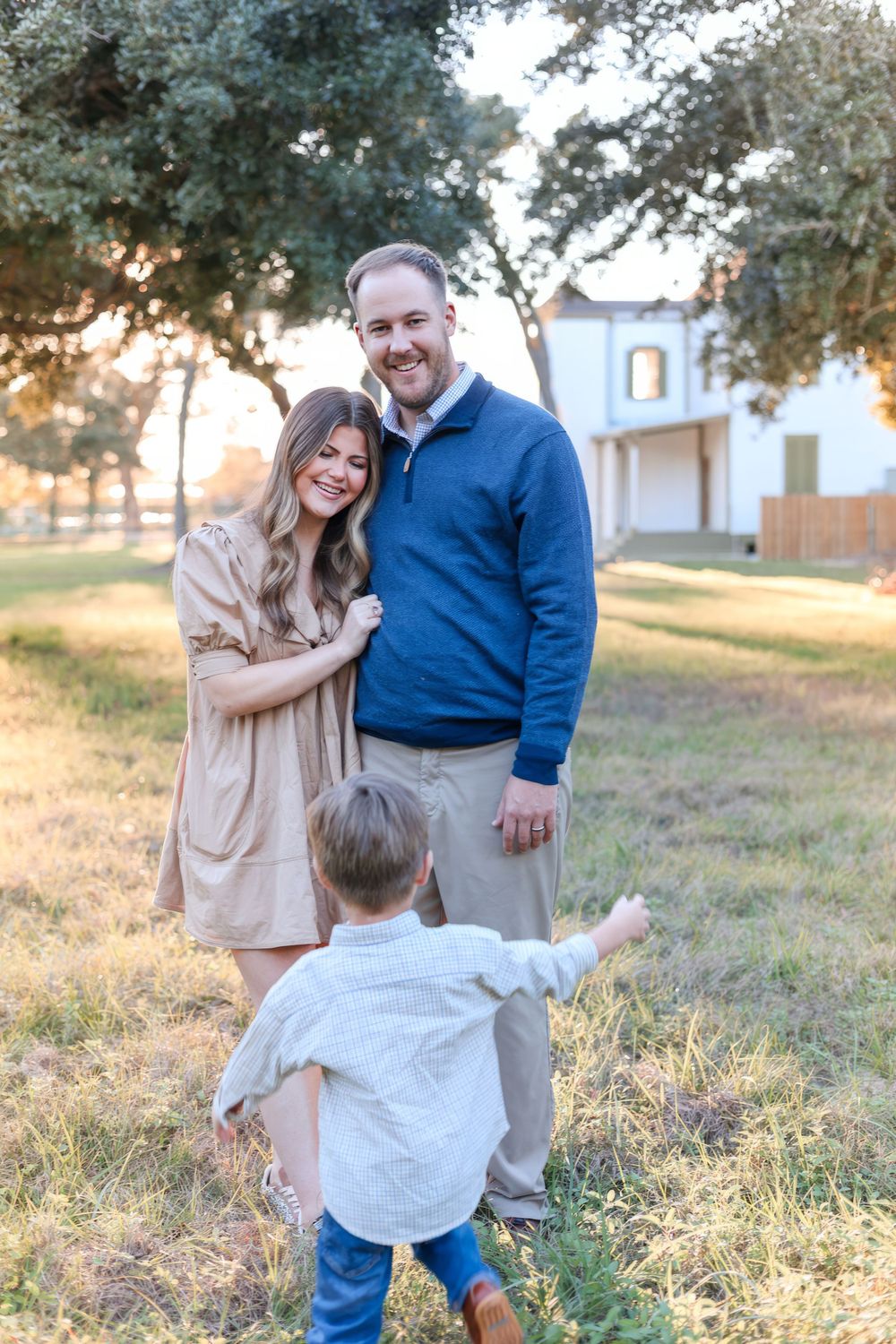 Family enjoying a sunset moment together in front of a white building. Family photography session.