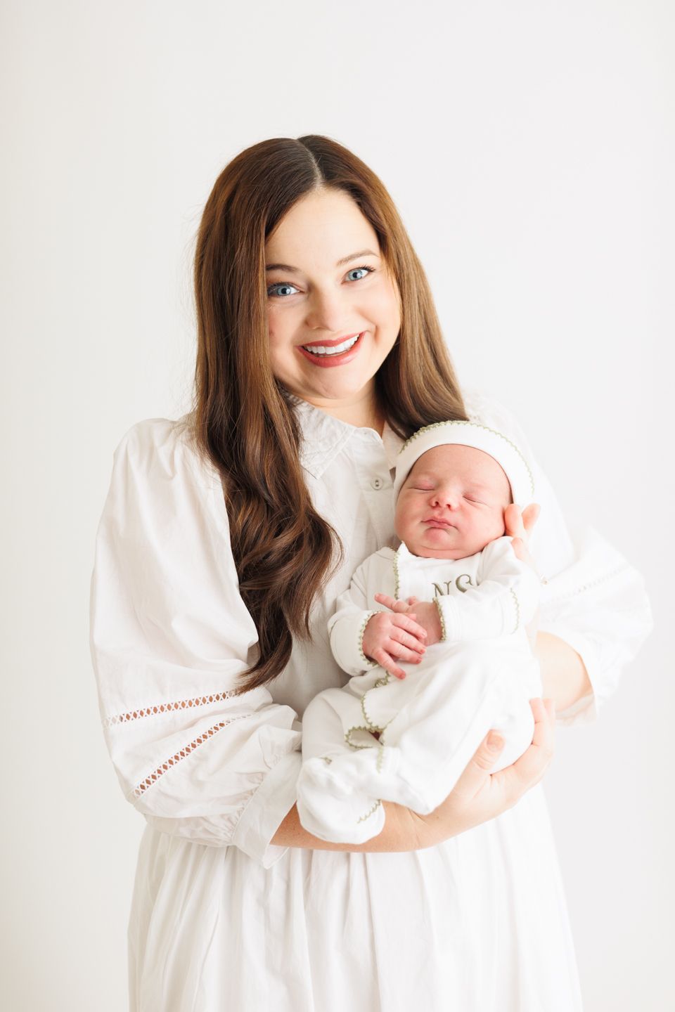 A mother in a white dress holds her sleeping newborn baby in a series of three tender portraits against a white backdrop.