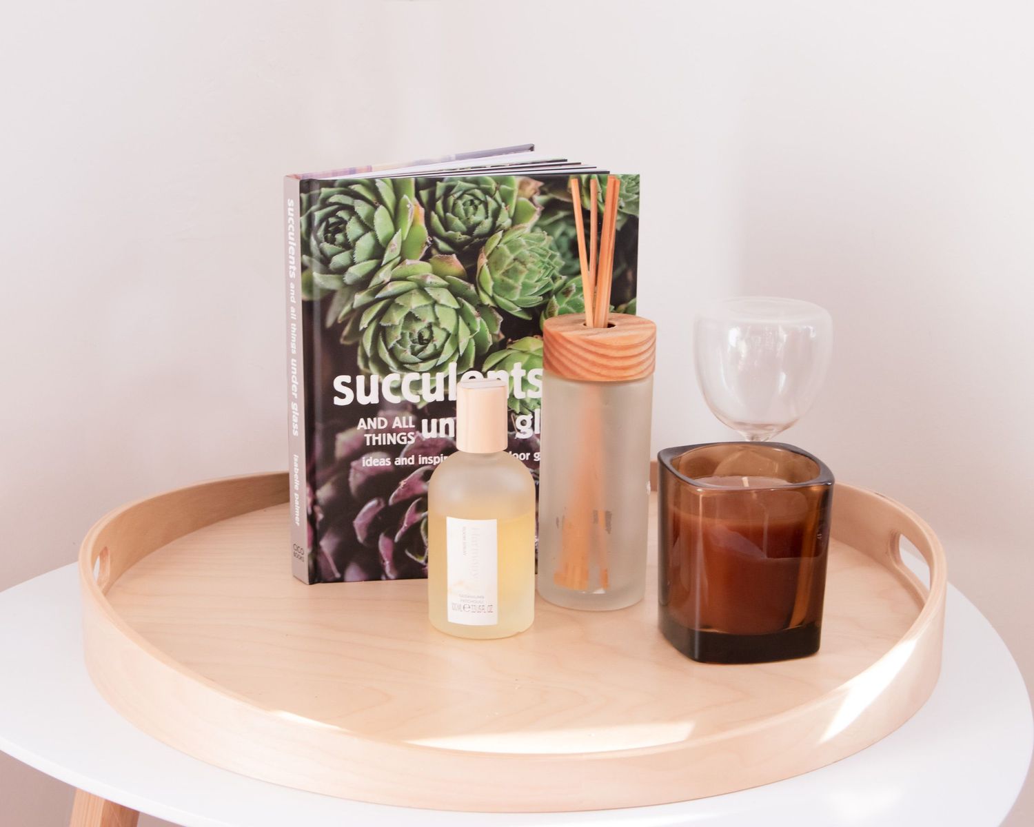 Decorative succulent plants and candles arranged on light colored surface.