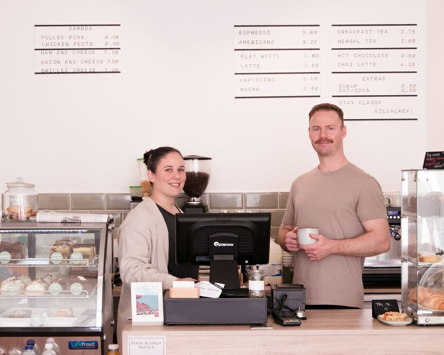 Coffee shop counter setup with equipment and display cases in a bright interior.