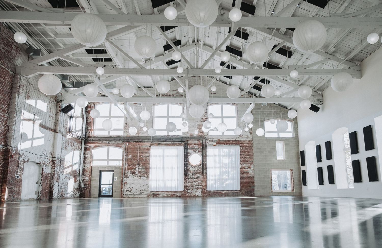Spacious industrial loft space with exposed brick walls, white ceiling beams, and large windows providing natural light.  Halo at the Point.