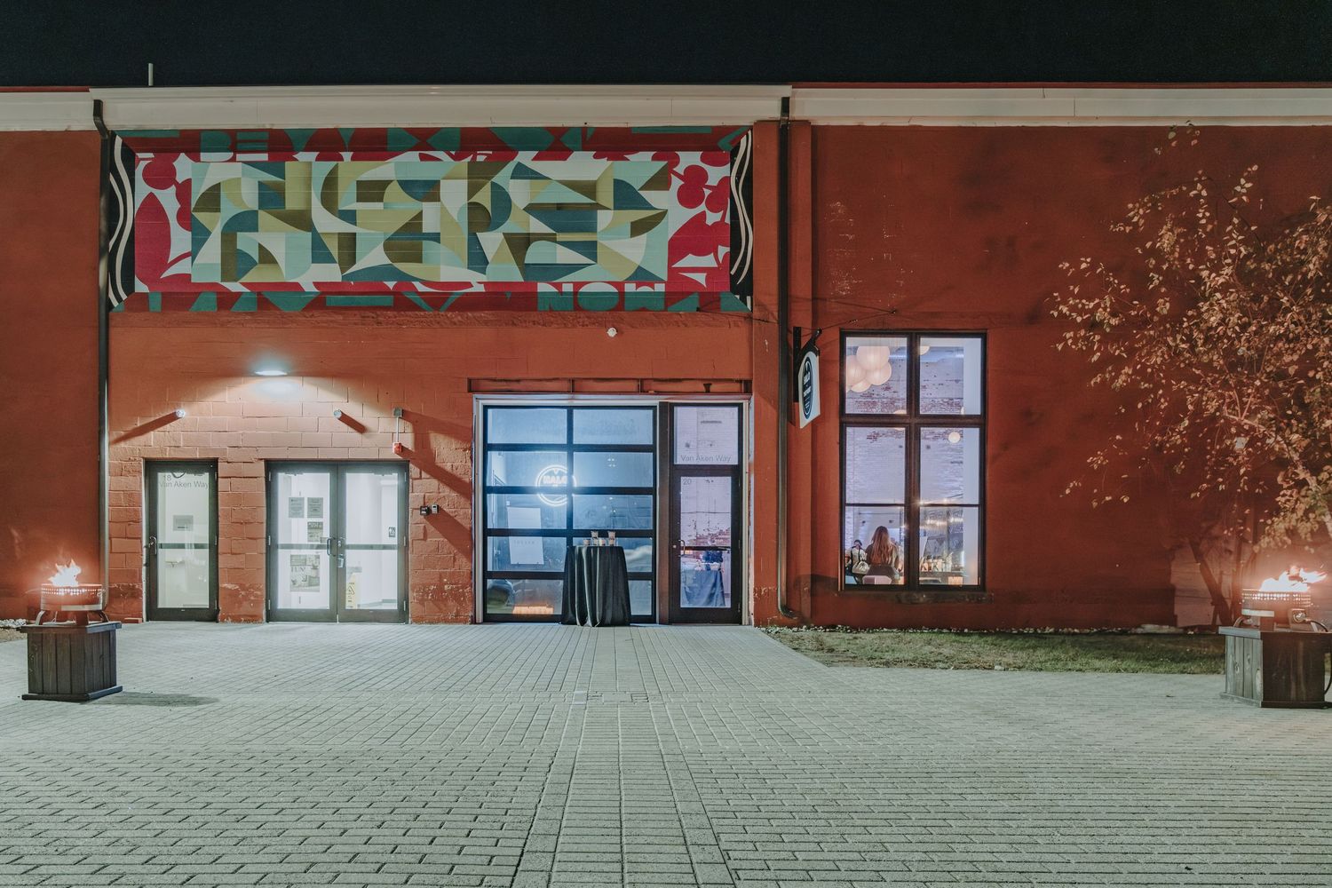 Modern entrance to a brick building with colorful graffiti artwork above the glass doors at night.  Photo taken at Halo at the Point, Maine.