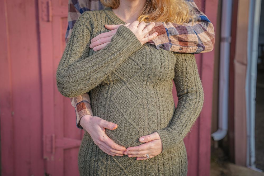 Close up of pregnant belly in green knitted sweater dress.