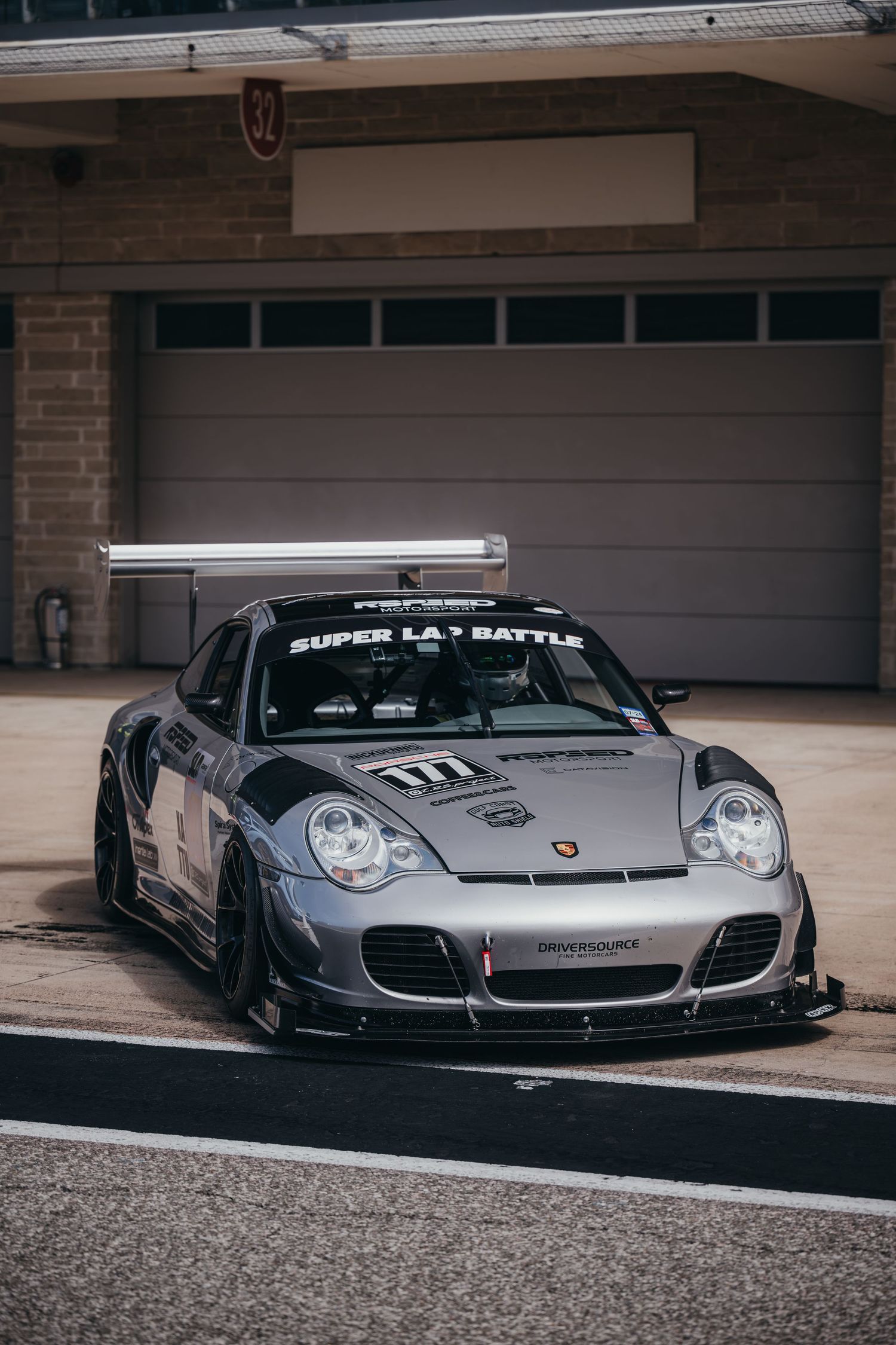 Modified Porsche sports cars in silver and gray parked in garage setting.