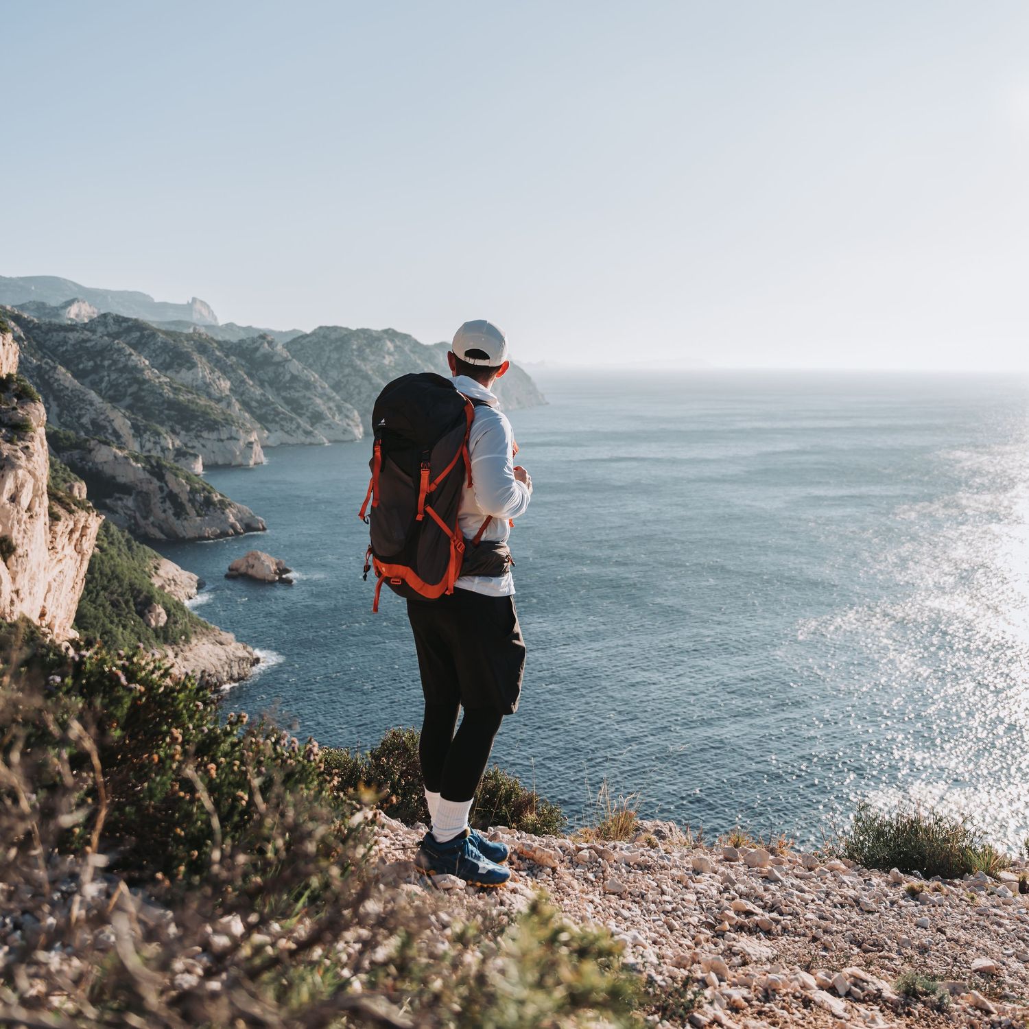 photo d'un jeune homme qui pratique la randonnée et qui regarde la mer du haut d'une falaise