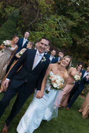 Wedding party posing outdoors with bridesmaids in blush dresses.