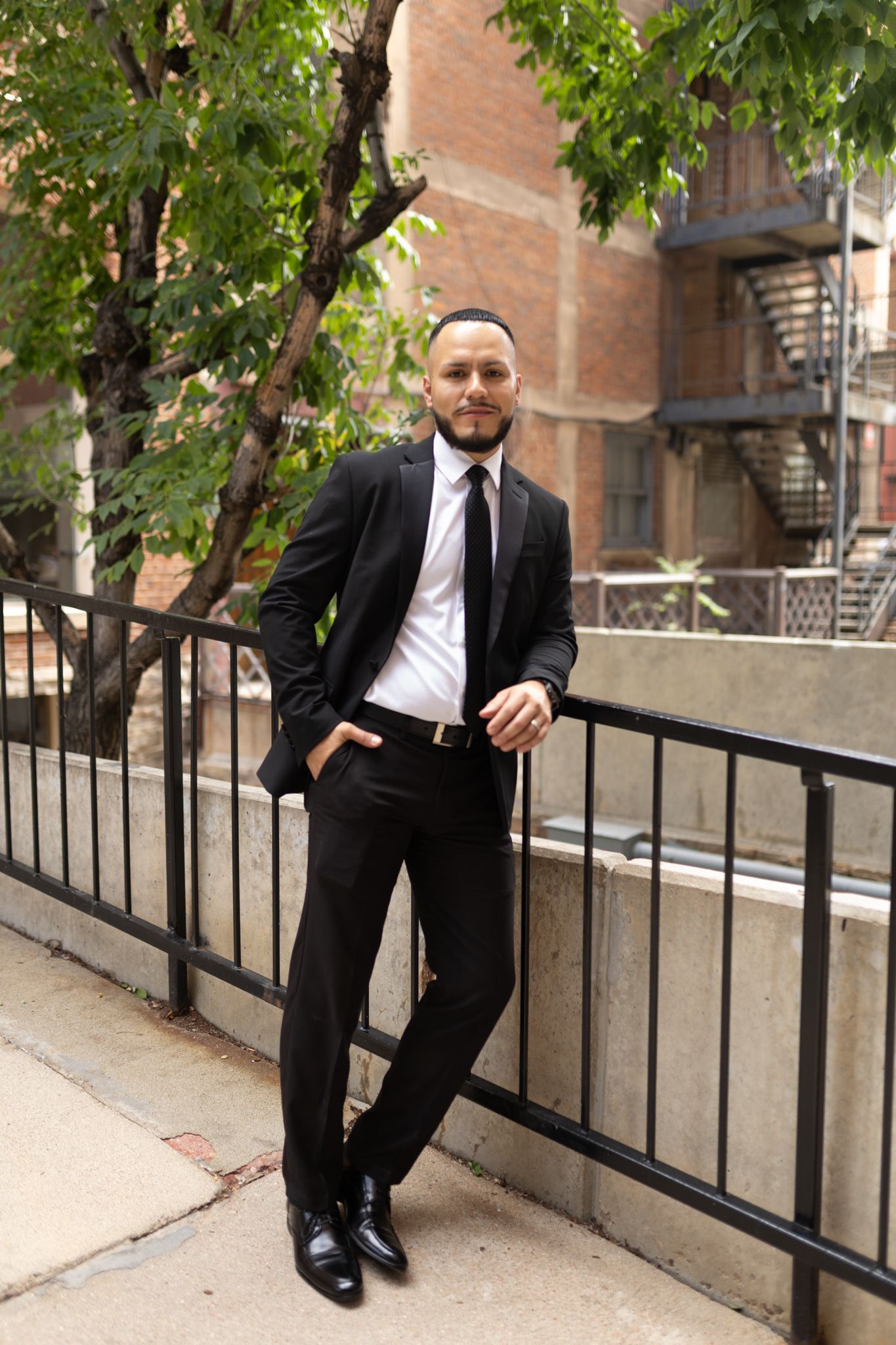 Man poses for the photo while leaning against a fence