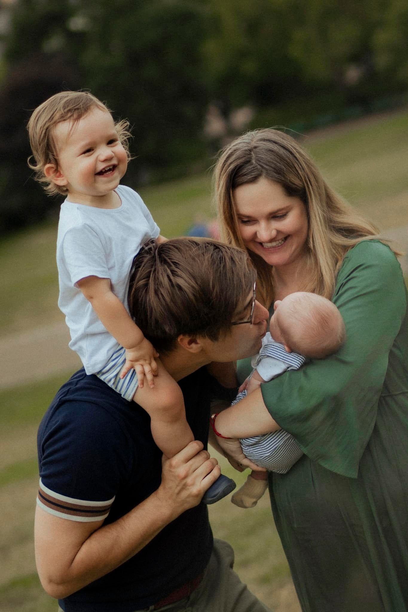Candid outdoor family moment showing parents playing with their children on a sunny day.