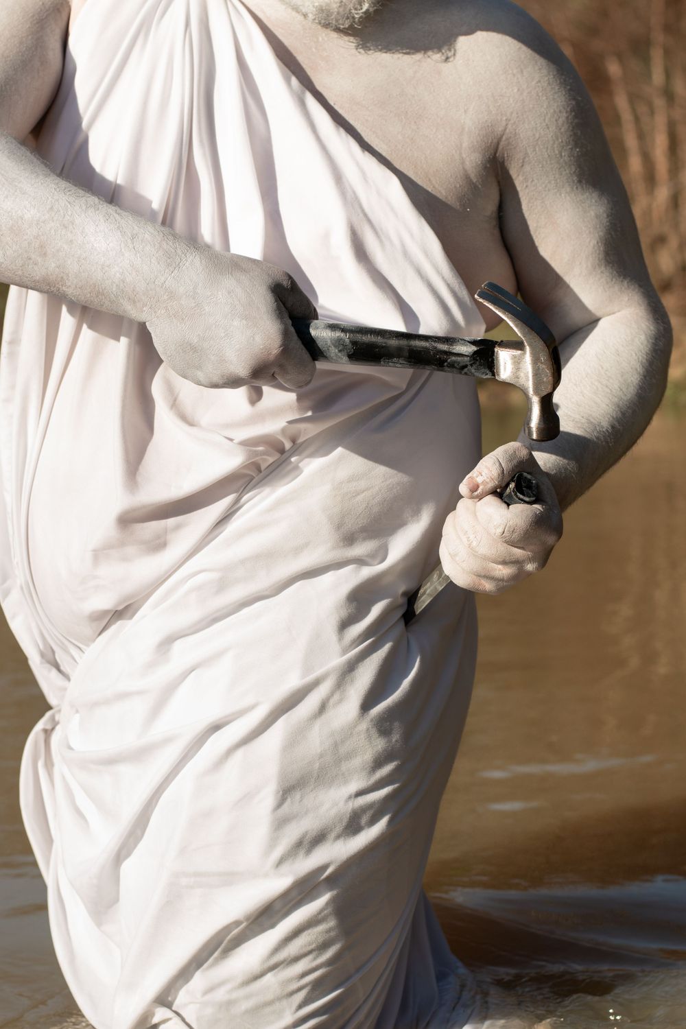Figure in white clothing draws a handgun from their waistband in dramatic lighting and composition.