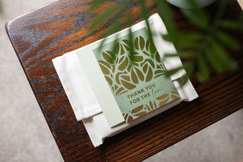 A decorative floral wedding monogram design printed on white paper resting on a wooden surface.