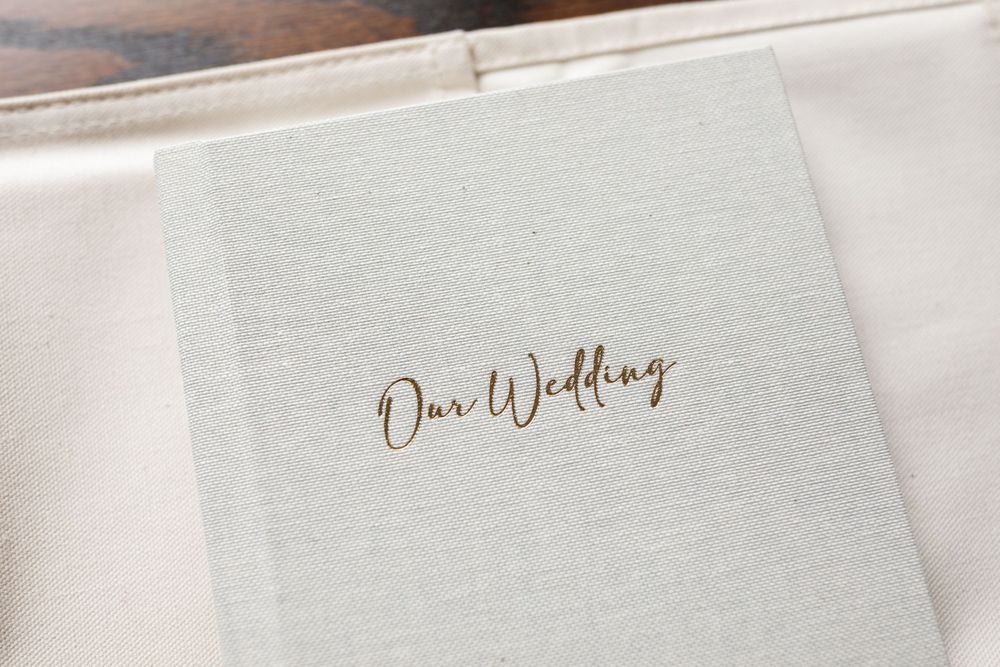 An elegant wedding album cover with gold 'Our Wedding' text on textured white paper.