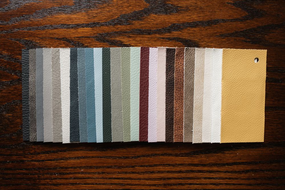 Color swatch samples arranged in a row showing neutral and muted tones on dark wood.