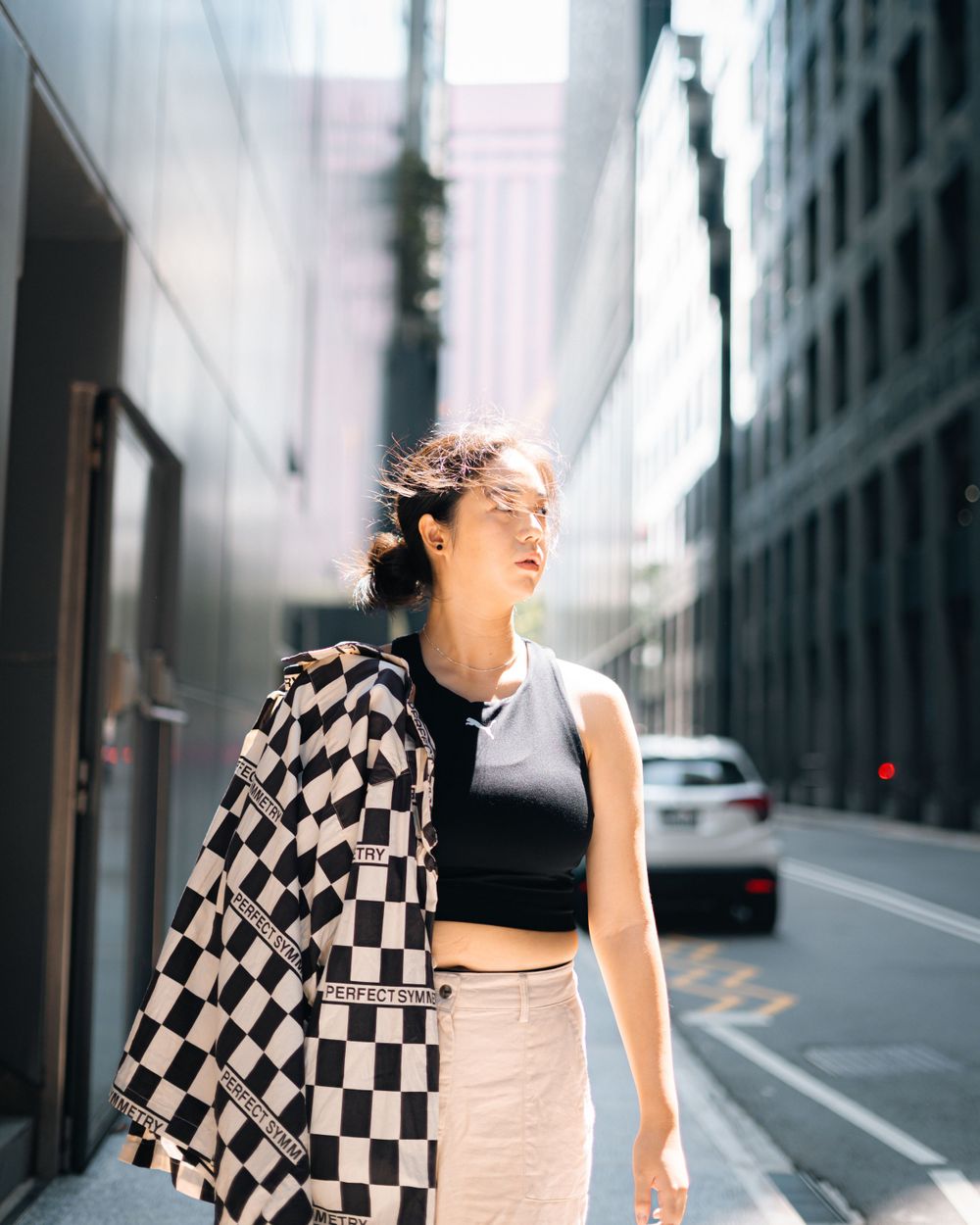 Fashion portrait in city street wearing black crop top and checkered jacket.