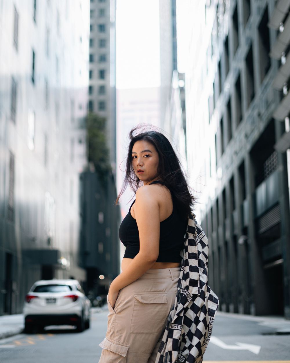 Street style portrait with checkered jacket and crop top in urban setting.