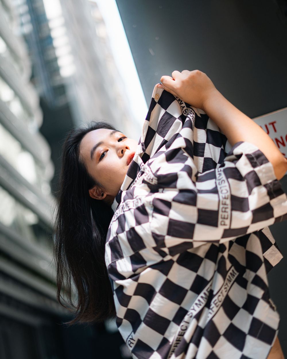 A fashion portrait featuring a black and white checkered jacket in an urban setting with dramatic lighting.
