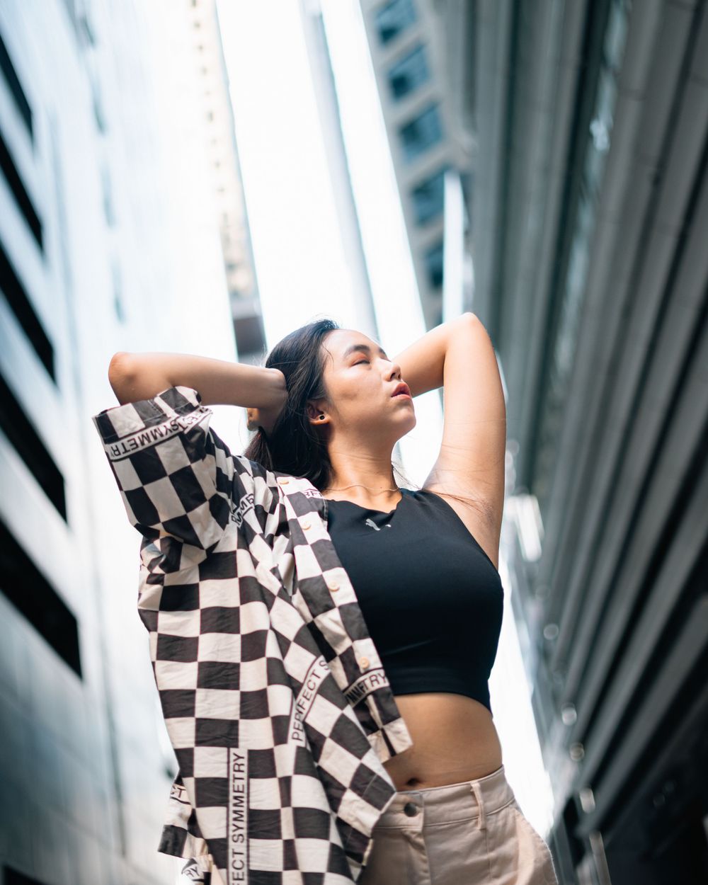 Athletic urban fashion shoot with a checkered overshirt and black crop top against architectural elements.