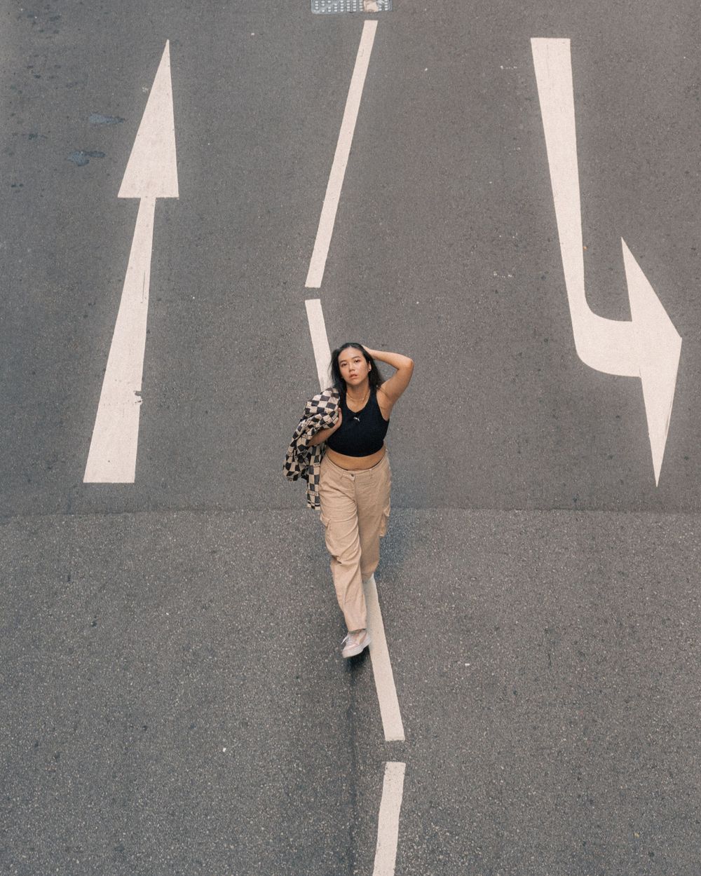Street photography with directional arrows painted on asphalt creating leading lines in urban composition.