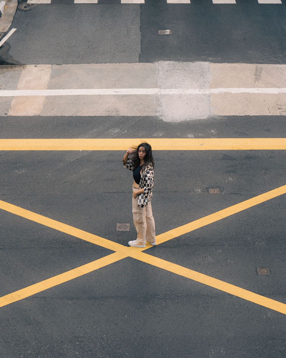 Aerial view of fashion photography on yellow road markings creating geometric patterns.