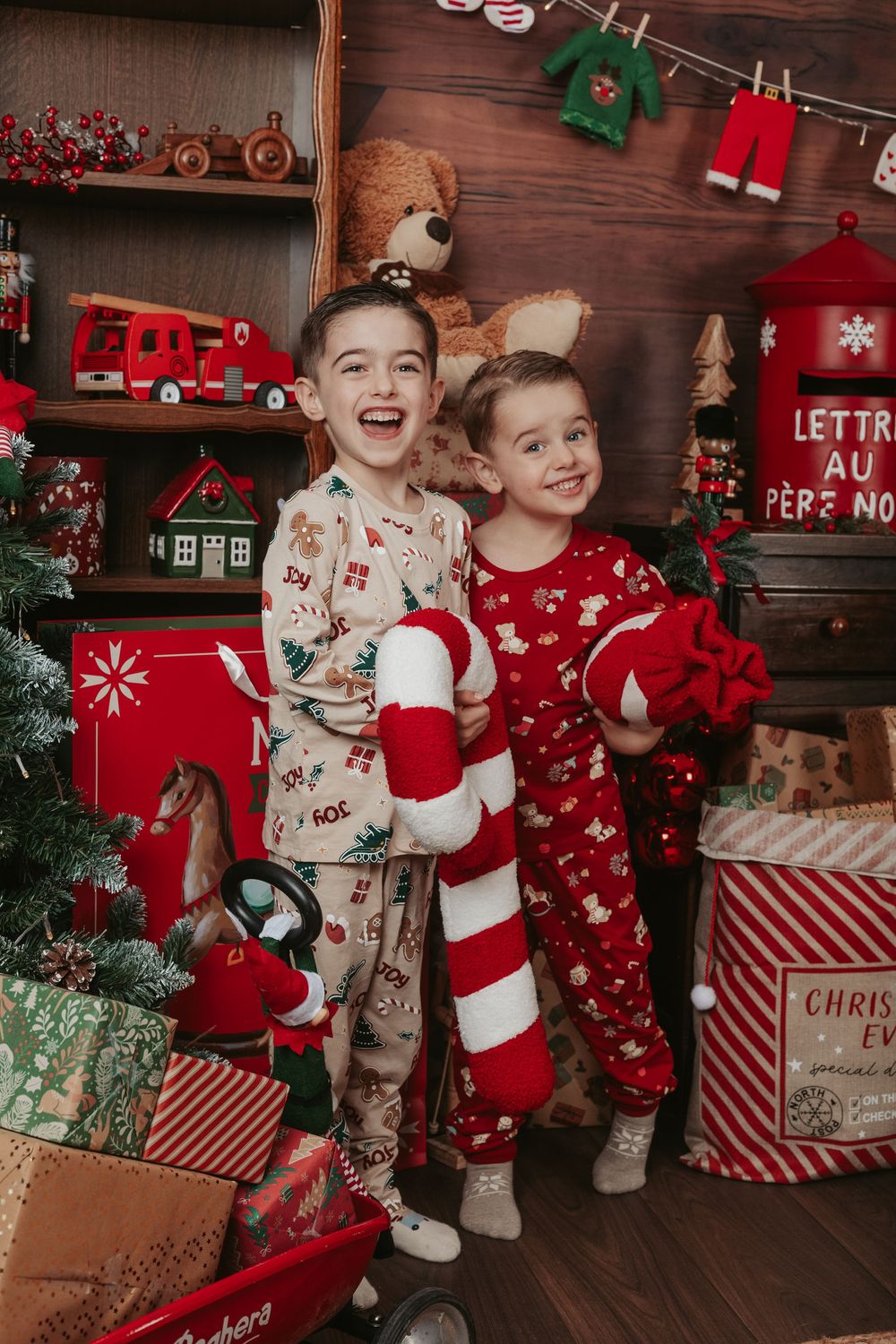 Cozy Christmas scene with children in holiday pajamas surrounded by festive decorations and candy cane props.
