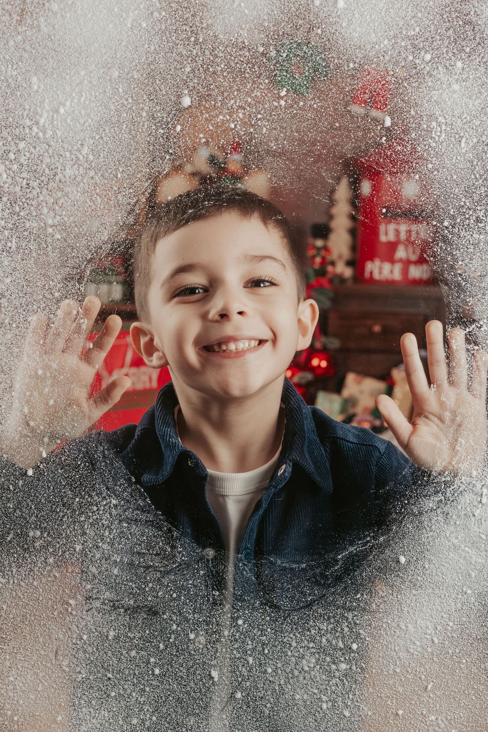 A sequence of playful expressions through a frosty window with snow and winter holiday decorations in the background.