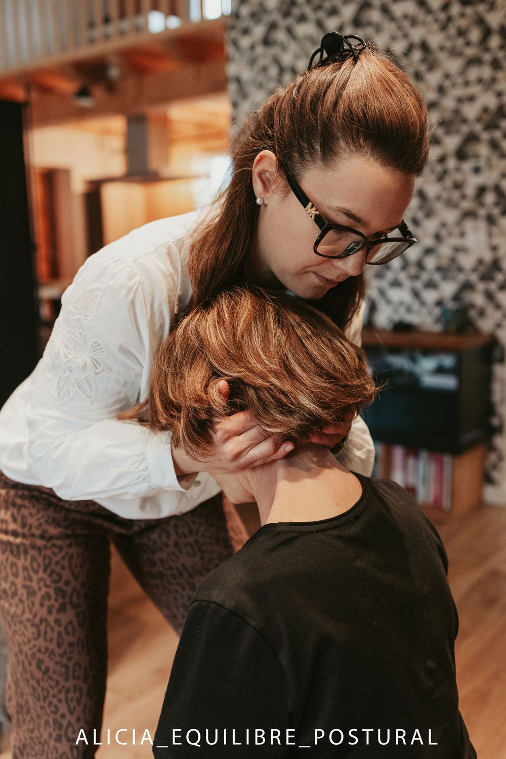 A massage therapist performs postural equilibrium treatment techniques on a client in a wellness studio.