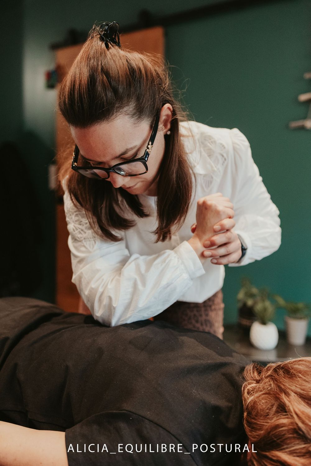 Chiropractor performs therapeutic massage treatment on patient's back in professional wellness clinic setting.