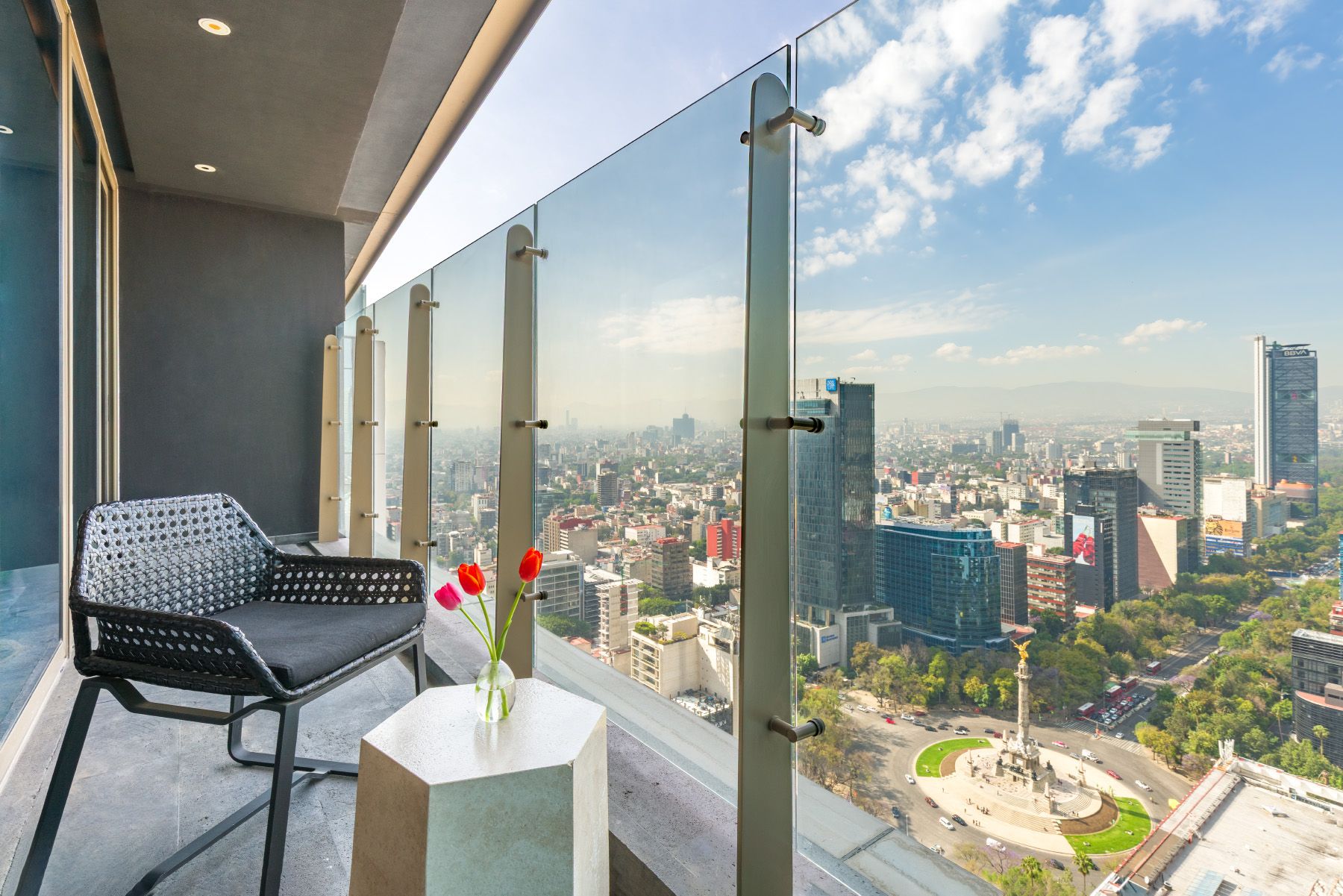 Elegant balcony at Sofitel Mexico City Reforma with glass railing overlooking urban cityscape with modern skyscrapers.