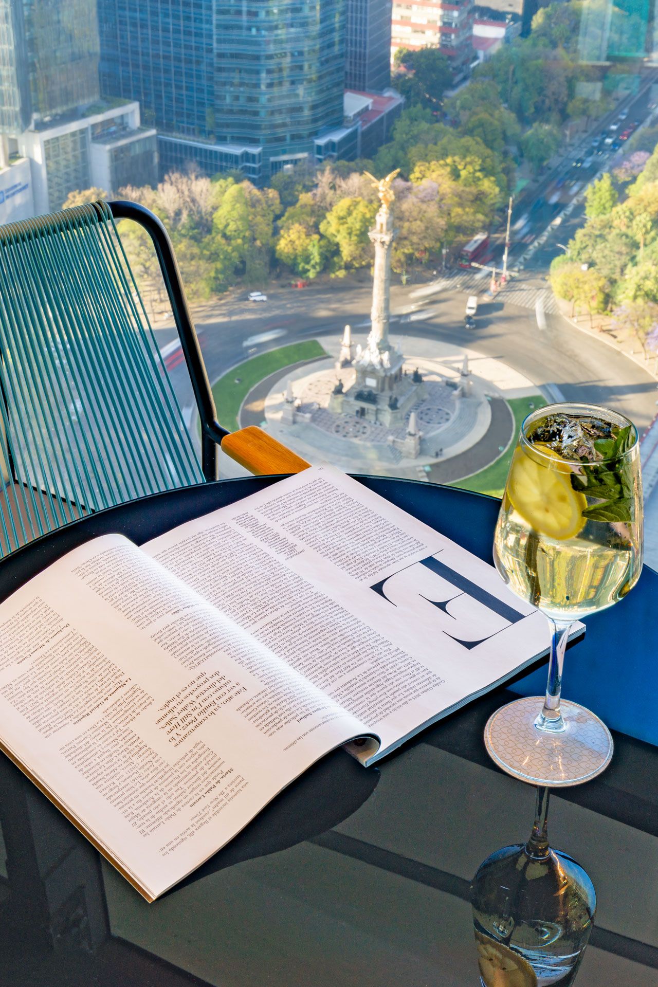 Aerial view from Sofitel Mexico City Reforma of Insurgentes Angel with open book and coctail in foreground.