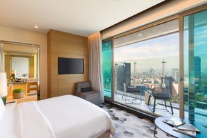 Luxurious hotel room with floor-to-ceiling windows offering stunning cityscape views and modern furnishings. Sofitel Mexico City Reforma.