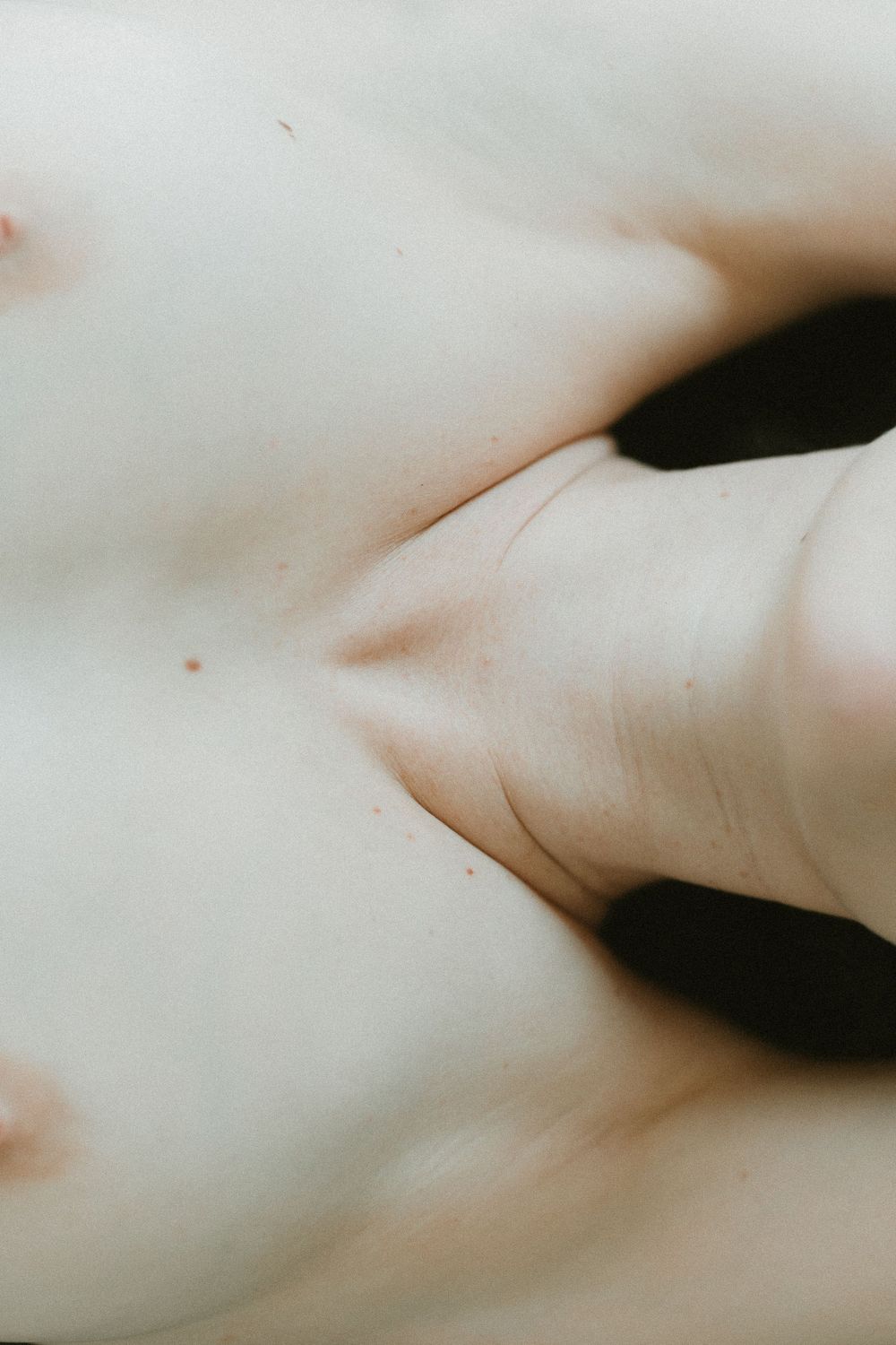 Abstract close-up photograph focusing on pale skin tones and natural curves.