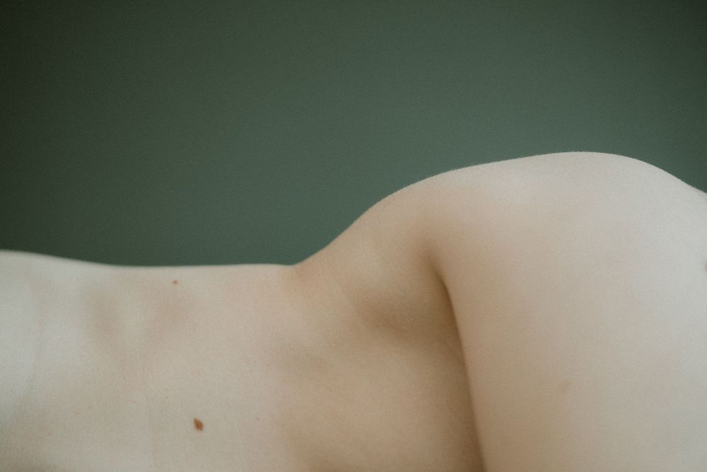 Close up abstract photo of pale skin curves and contours against dark background.