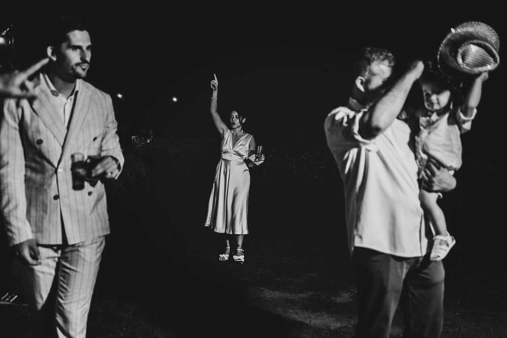 A black and white photograph showing multiple performers illuminated on a darkened stage during a show.