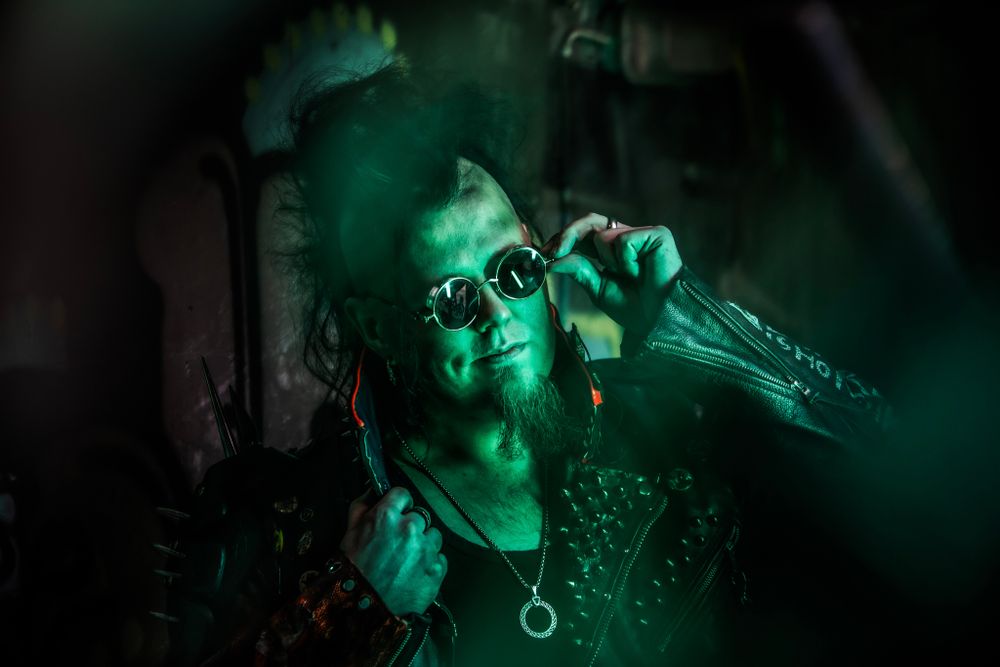 A singer performs on stage illuminated by dramatic green lighting while holding a microphone during a concert performance.