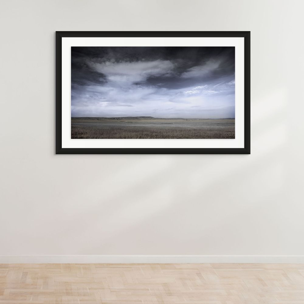 Dramatic stormy clouds over an empty prairie landscape extending to the horizon.