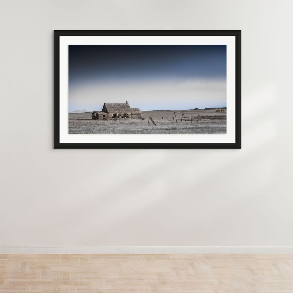 A lonely farmhouse and barn stand isolated in a desolate winter landscape under a moody gradient sky.
